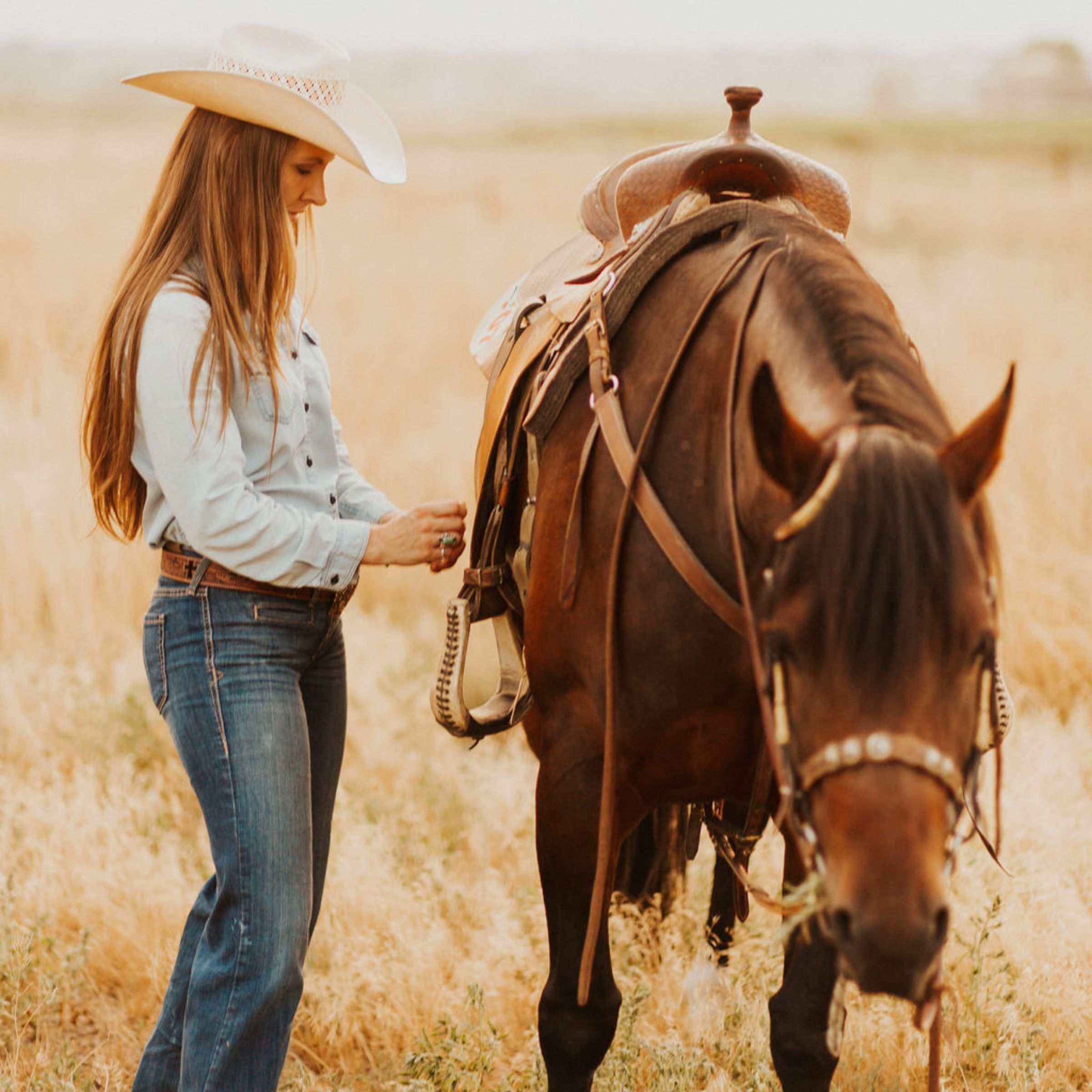 Tall woman saddling horse in field Faith-Hanan-Spiritual-Growth-for-Women