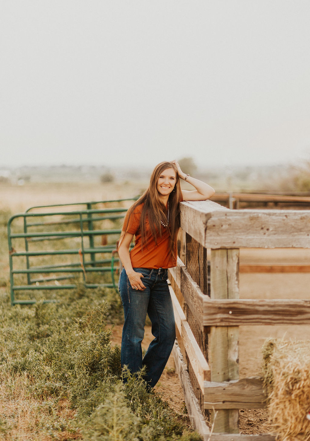 Smiling and happy woman with long brown hair leaning on fence teaching small businesses an SEO strategy for sustainable growth